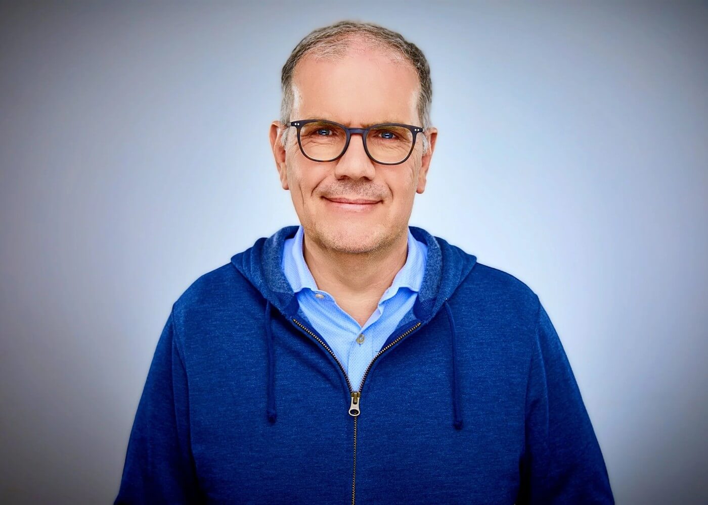 Björn Ognibeni locker gekleidet im blauen Kapuzensweatshirt