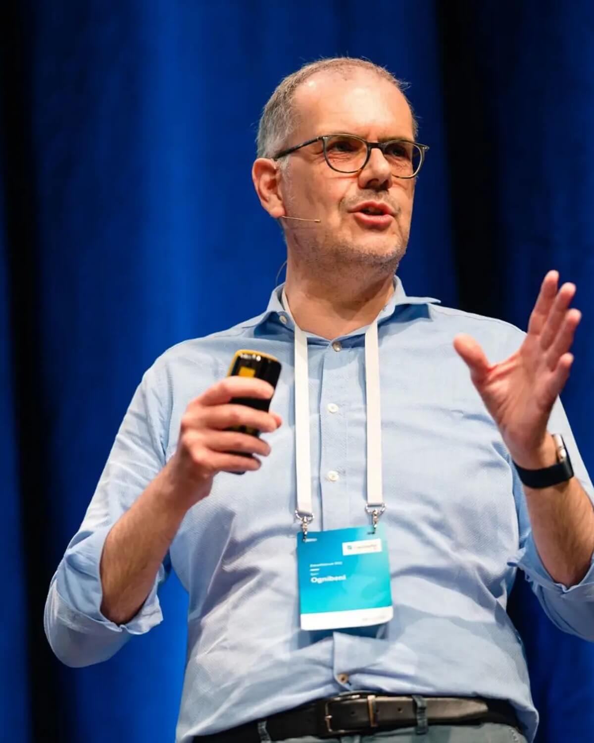 Björn Ognibeni auf der Bühne, Presenter in der Hand, vor blauem Vorhang