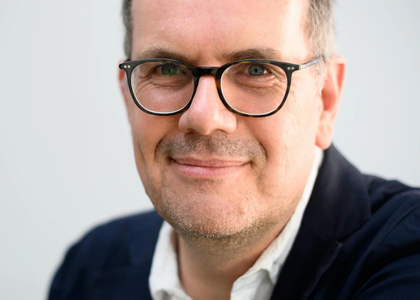 Björn Ognibeni im Porträt, freundlich lächelnd mit Brille