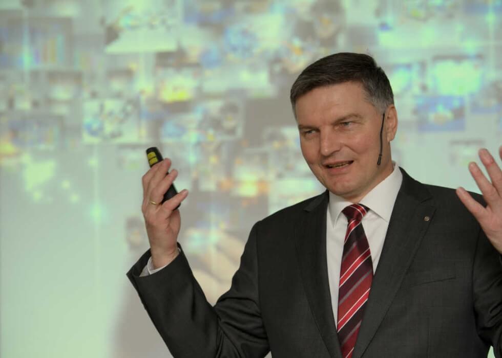 Johann Hofmann mit Presenter in der Hand vor einer projizierten Prozessgrafik