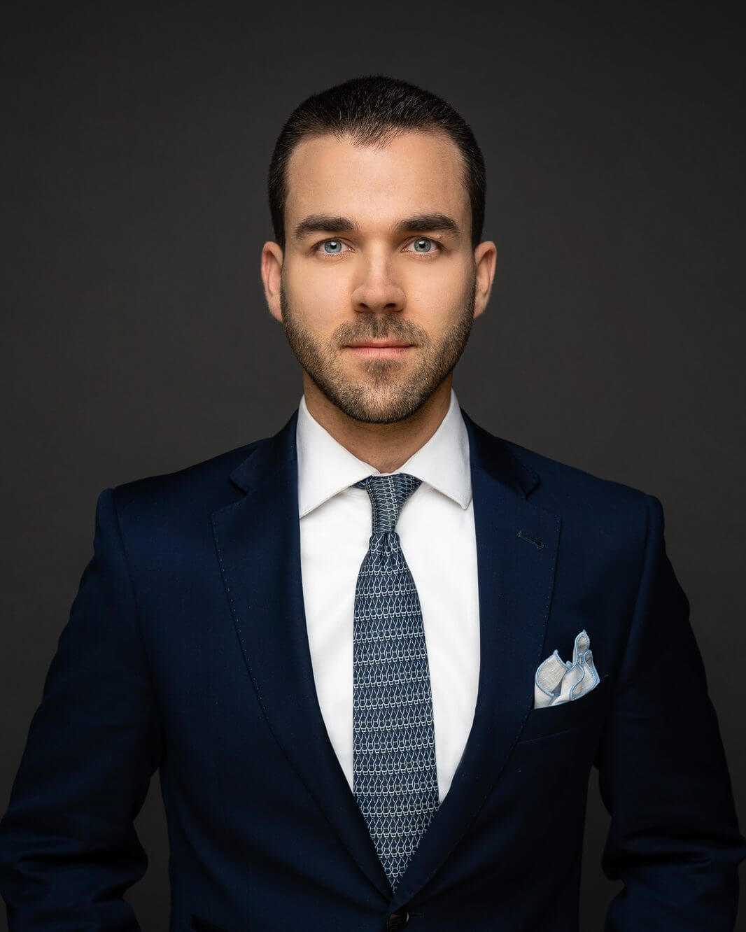 mark-t-hofmann-keynote-speaker-anfrage-portraet Porträt von Mark T. Hofmann im dunkelblauen Anzug mit gemusterter blauer Krawatte vor dunkelgrauem Hintergrund