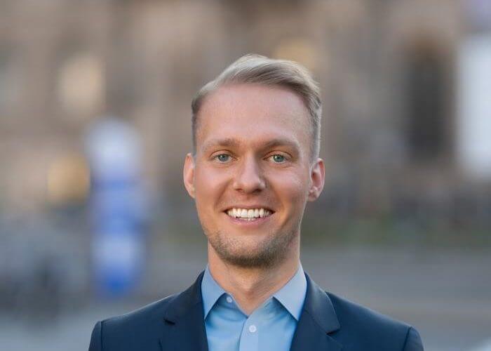 Porträt von Nico Marquardt im dunkelblauen Sakko, lächelnd